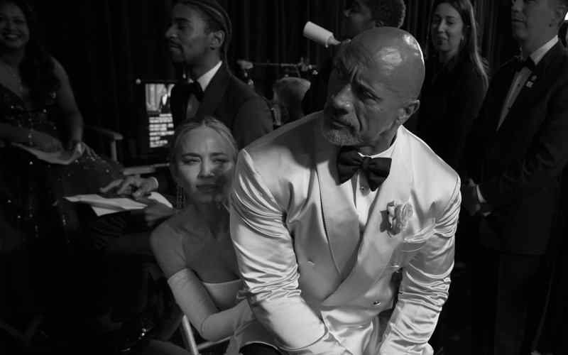 The Rock Spotted Sitting On Emily Blunt’s Lap While Backstage At The Oscars